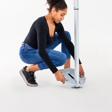 The woman attaches the 10 kg base plate to the folding gazebo.